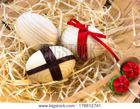 Easter eggs with ribbon and red flowers. Background birch bark and straw