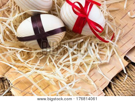Easter eggs with ribbon and red flowers. Background birch bark and straw