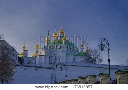 Golden dome with a golden cross on the territory of the Kiev-Pechersk Lavra against the blue sky