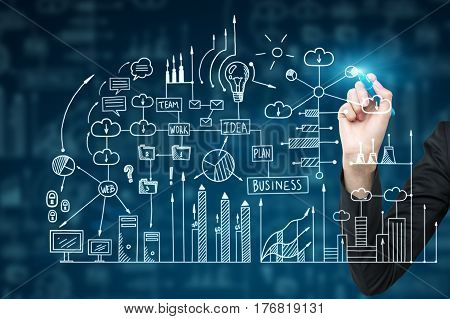 Hand of a businessman in a dark suit is drawing a business scheme on a glassboard with a glowing marker.