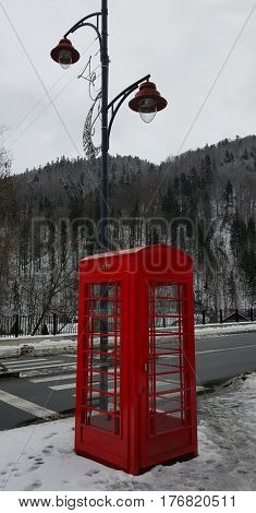 Red telephone box in street with historical architecture in Sinaia Romania isolated.