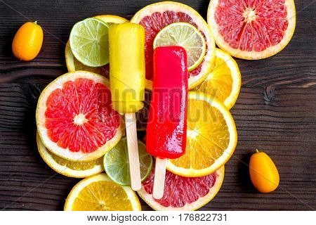 homemade citrus popsicles with fresh fruit slices on wooden table background top view
