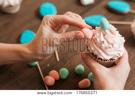 Masterclass of preparing decorated cupcakes with white cream on wooden table. Cookery arts. Easter gift, small business, delivery of sweets, craftmanship concept