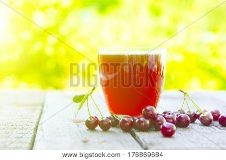 Homemade Cherry Juice In Glass With Freshcherry On Wooden Table In Garden. Fresh Fruit Drink