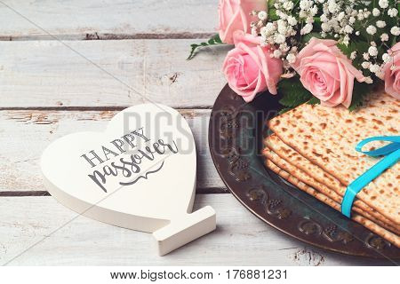 Jewish holiday Passover Pesah concept with matzoh rose flowers and heart shape sign over wooden background