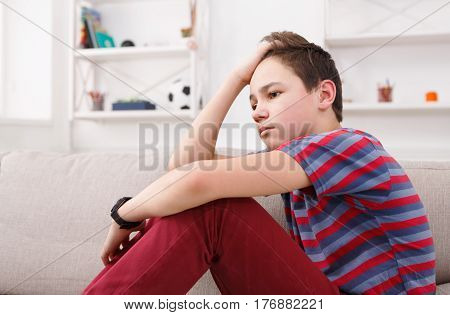 Unhappy lonely teenage boy at home, thinking about something, pubertal period, psychological problem. Lost in thoughts.