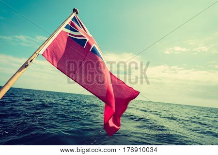 The uk red ensign the british maritime flag flown from yacht sail boat blue sky and baltic sea. Summer and travel voyage