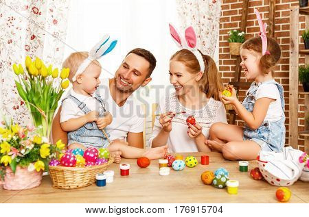 Happy easter! family mother father and children having fun paint and decorate eggs for holiday