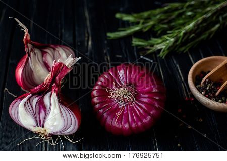 Red onions, rosemary, and spices on a dark table. close up