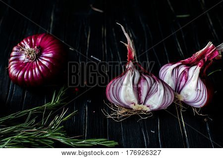 Red onions, rosemary on a dark table. close up