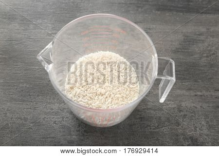 White rice in measuring cup on table