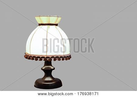 Old wooden desk lamp isolated on a gray background with a light bulb turned on