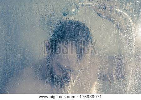 Stressed Man Taking A Shower Standing Under Flowing Water And Holding His Head In Shower Cabin Behin