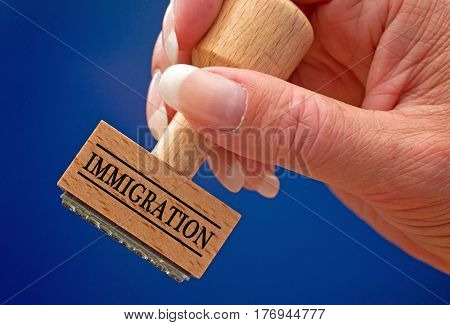 Immigration - female hand with stamp on blue background