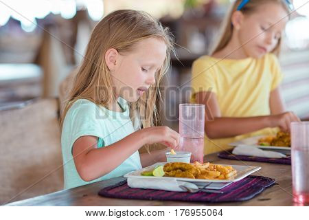 Adorable little girl having breakfast at outdoor cafe