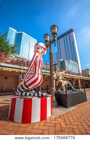 Hong Kong, China - December 5, 2016: Miss 13 Dots and Guo Jing, statues of famous characters, in Hong Kong Avenue of Comic Stars, Kowloon Park. Urban skyline, Tsim Sha Tsui. Sunny day, blue sky.