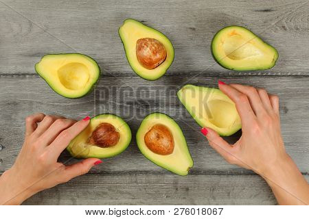 Tabletop View, Woman Hands With Red Nails Holding Avocados Cut In Half, More Halves, Some Of Them Wi