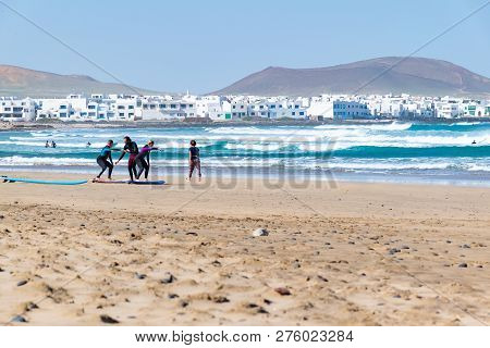 Famara Beach, Lanzarote Island - Dec 15 2018: Surf Lesson. Learners Are About To Enter The Water At 