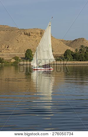 Traditional Egyptian Felluca Sailing Boat On River Nile With Reflection At Aswan