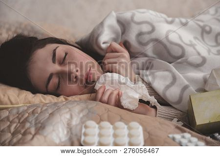 A Young Girl Wrapped In A Blanket And During Illness And Checks The Temperature Looking At The Therm