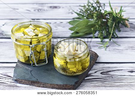 Marinated Feta In A Glass Bath On A Wooden Background.