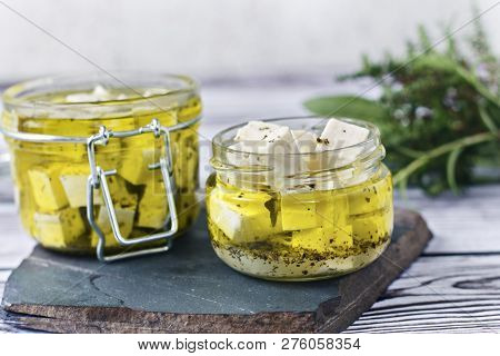 Marinated Feta In A Glass Bath On A Wooden Background.