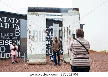 Berlin, Germany - March, 2018: Tourists Looking At A Piece Of The Berlin Wall At The  Entrance Of Th