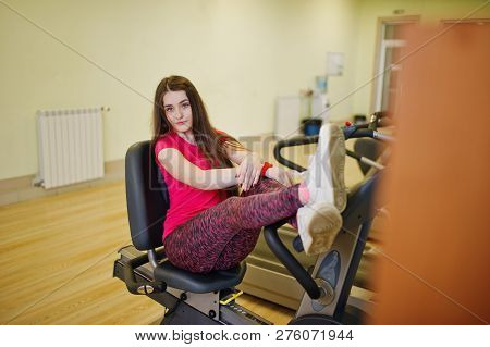 Young Sport Girl Workout In Gym. Fitness Woman Doing Exercises On Stationary Bicycle.
