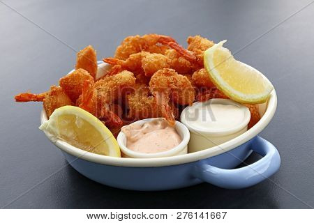 Close Up Portion Of Battered And Breaded Shrimps With Dipping Sauces Served In Cooking Pot Over Blue