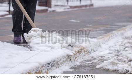 Man With Snow Shovel Cleans Sidewalks In Winter.