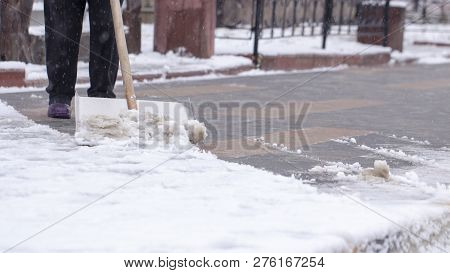 Man With Snow Shovel Cleans Sidewalks In Winter.