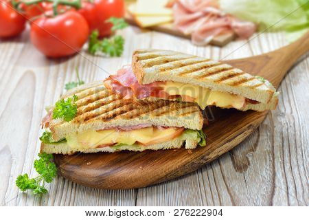 Grilled And Pressed Toast With Smoked Ham, Cheese, Tomato And Lettuce Served On Sandwich Paper On A 