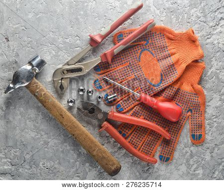 Working Tool On A Gray Concrete Surface. Work Gloves, Hammer, Nippers, Screwdriver, Pliers, Screwdri