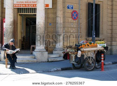 Nicosia, Cyprus - March 17, 2018: A Man Selling Fruit From A Stall On A Cart Sits On The Pavement In