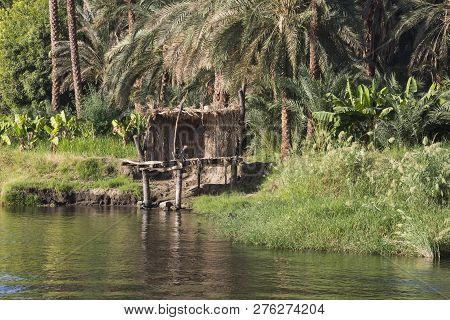 View Across River Nile In Egypt Through Rural Countryside Landscape With Reflection In Water And Sma