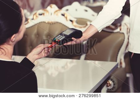 Credit Card Terminal For Cashless Payments. Cashiers Hand Holds Credit Card Reader On Restaurant Bac