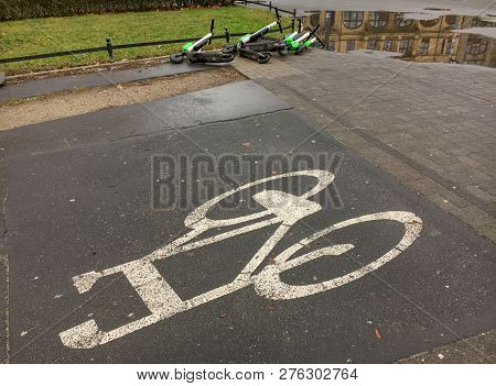 An Abandoned Dirty Electric Scooters Lie On The Ground Of A Street Behind The Sign 