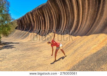 Blonde Woman Enjoying Surfing On Wave Rock, A Natural Rock Formation That Is Shaped Like A Tall Brea