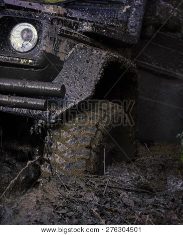 Extreme Entertainment Concept. Offroad Tire Covered With Mud Overcomes Obstacles On Nature Backgroun