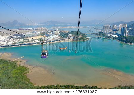 Ngong Ping Cable Car With Tourists Over Harbor, Mountains And City Background, To Visit The Tian Tan