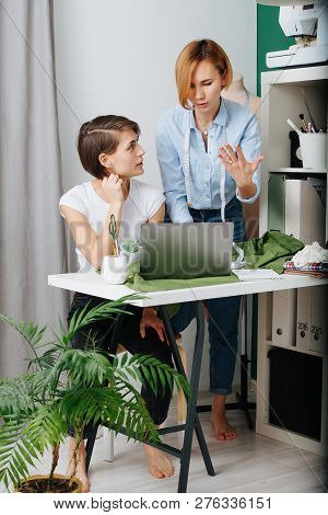 Young Female Fashion Designer Reviewing Clothing Styles With A Customer To Choose Design. They Both 