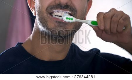 Man Brushing His Teeth In Front Of Mirror In Bathroom. The Reflection Of A Young Man In A Mirror, A 