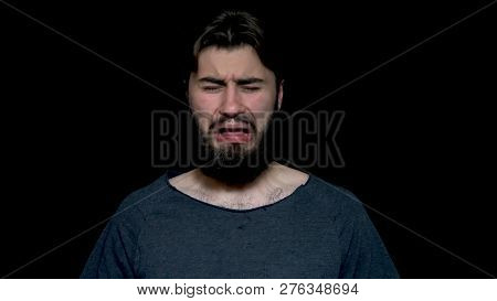 Young Bearded Man Sniffing His Armpit, Something Stinks Very Bad, Isolated On Black Background. Nega