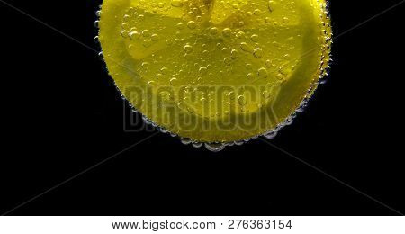 A Slice Of Lemon With Bubbles Isolated On Black Background