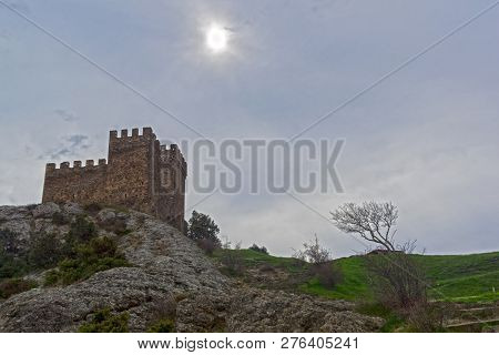 Genoese Fortress In Sudak, Crimea. Consular Castle And A Lonely Tree Against A Cloudy Sky. Early Apr