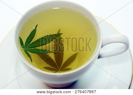 Cannabis Tea. Marijuana Tea. Hemp Tea with a Marijuana Leaf in a white Tea Cup. Isolated on white. Room for text. 