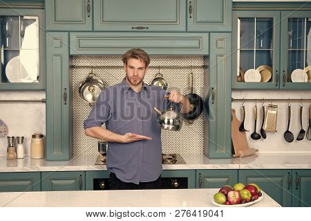 Man In Blue Shirt Point Hand At Kettle. Kitchen Appliance And Furniture. Presenting Product, Online 