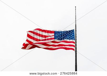 United States Flag Flying At A Half-staff Waving Against Gray Sky