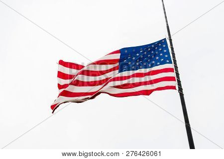 United States Flag Flying At A Half-staff Waving Against Gray Sky