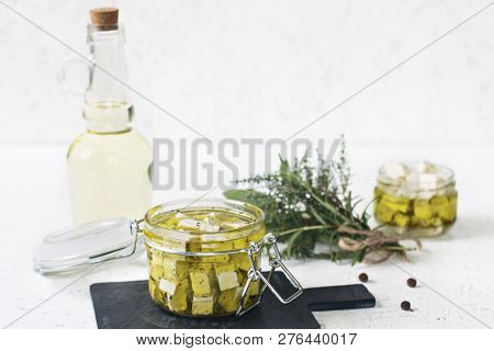 Marinated Feta In A Glass Jar, Spices And Flavored Olive Oil On A Wooden Background